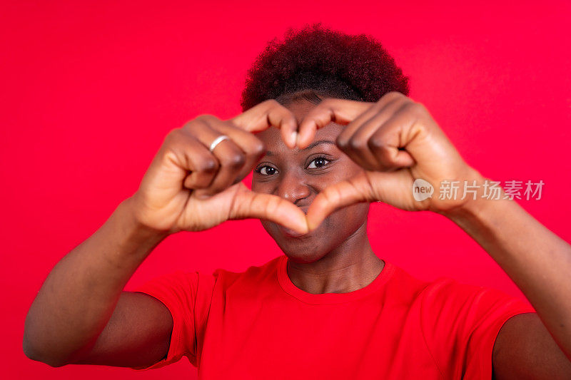 年轻的非裔美国妇女孤立的红色背景微笑和心脏手势，工作室拍摄
