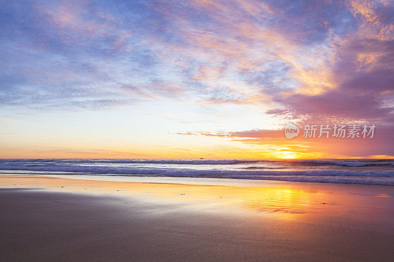 退潮时，湿沙滩上倒映着金色夕阳的海景