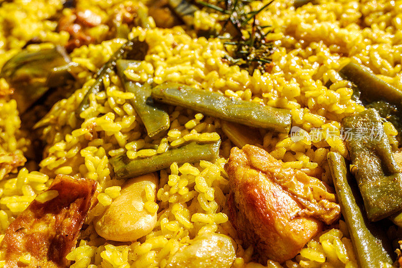 黄色的米饭配上肉和蔬菜，瓦伦西亚海鲜饭，典型的西班牙美食。