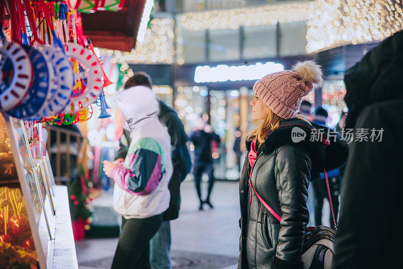穿着保暖衣服的妇女站在圣诞市场摊位前