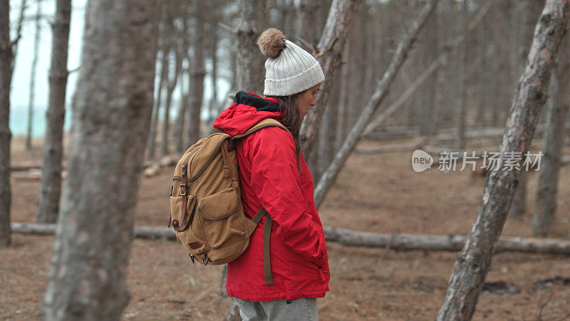 穿红衣服的女人在树林里徒步旅行。回归自然。