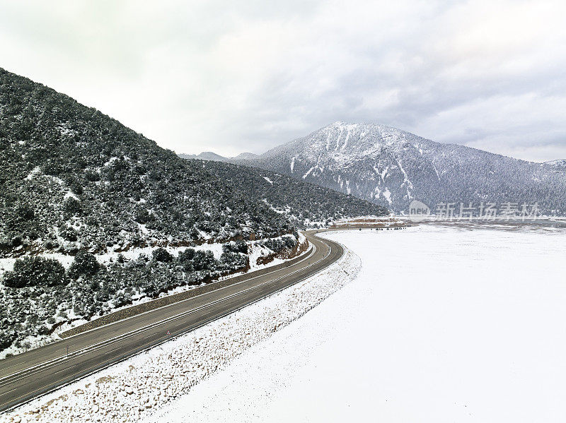 冬天结冰的湖泊和雪山之间的高速公路