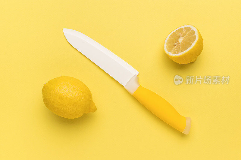 一把陶瓷刀，有白色的刀刃和黄色背景上切好的柠檬。