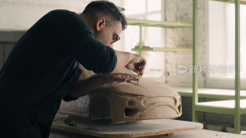 汽车设计师雕刻一个汽车模型使用有线工具雕刻出大块的粘土