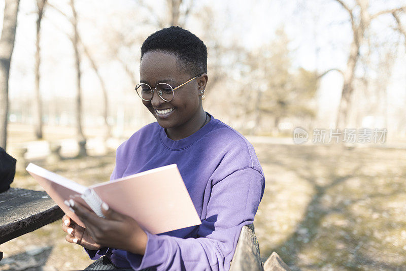 一个年轻的非洲妇女在公园里享受阅读的肖像