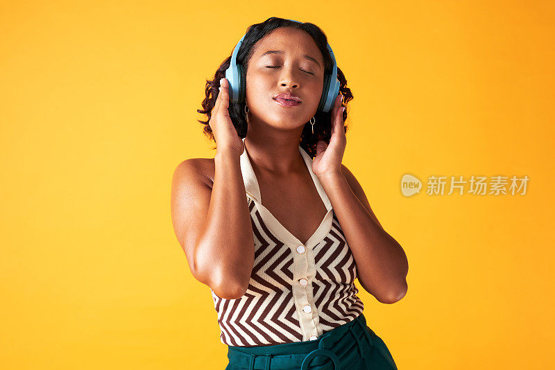 音乐，听和耳机与一个年轻的女人流媒体播客，广播或在线音频在演播室的黄色背景。互联网和科技带来的自由、放松和健康