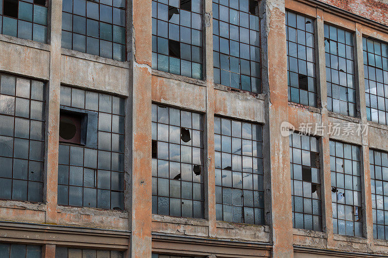 一座老建筑的窗户。窗户上有一个金属结构。玻璃碎了。墙在剥落。