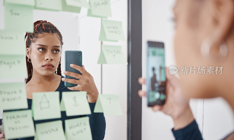悲伤，焦虑和女人在镜子前用手机沉思的反射照片在社交媒体上。抑郁的黑人女孩，脸上带着沮丧和不快的表情，在痛苦中思考自尊问题。
