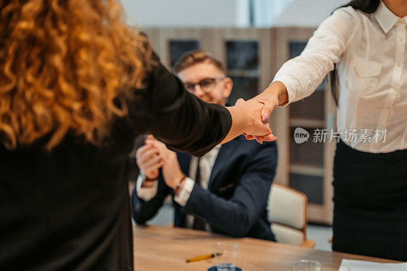 两位女商人在办公室握手敲定生意