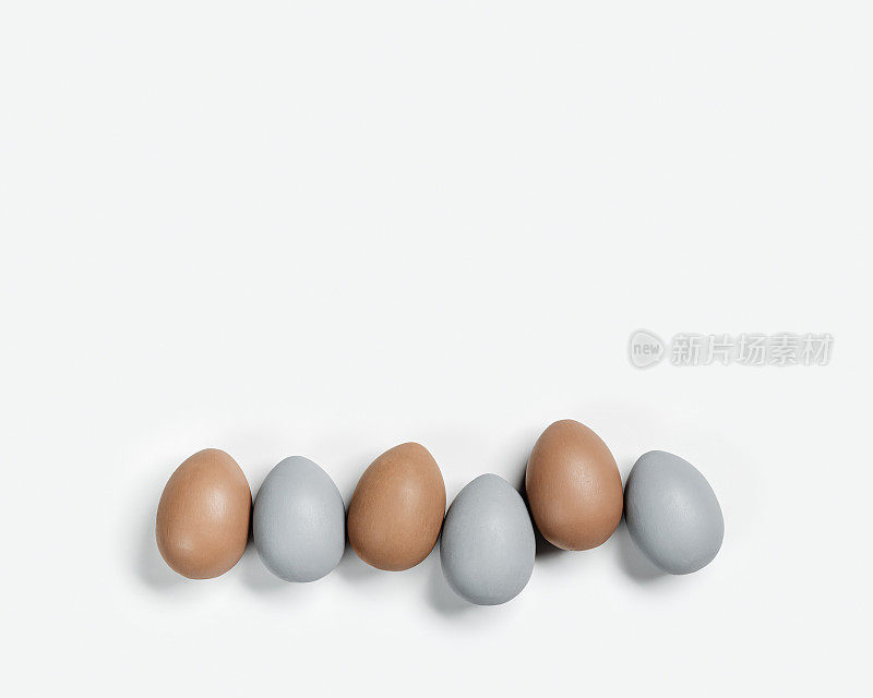 染色复活节彩蛋粉彩灰色，米色排在白色背景。复活节快乐，庆祝食物概念，鸡蛋中性的潮流色彩。俯视图