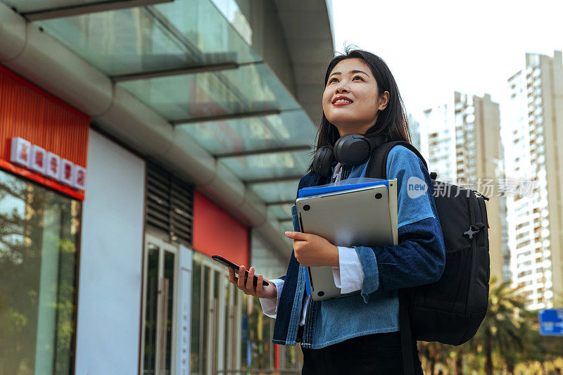 可爱的女大学生抬头，而站在户外的白天。