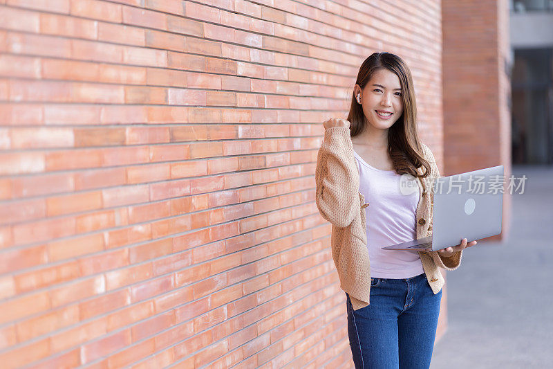 亚洲女学生在大学附近学习备考。通过连接到互联网的手机或笔记本电脑进行交流。知识来源丰富