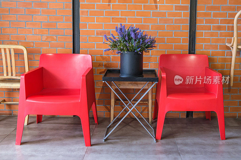 两把红色塑料扶手椅和一束人造薰衣草花