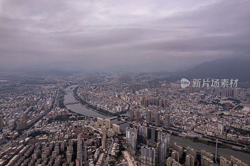 多云天，有河流的城市中人口密集的建筑物鸟瞰图