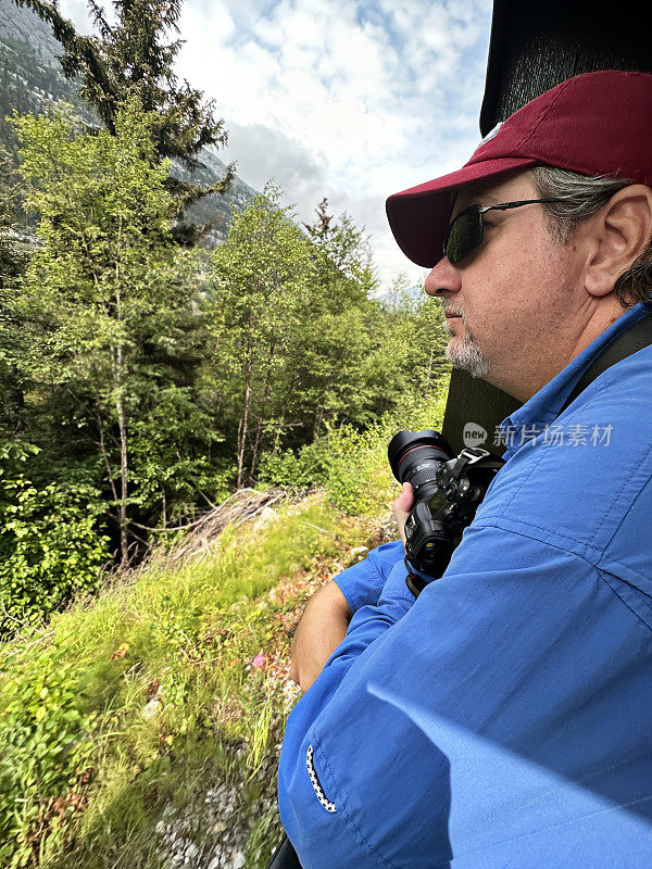 一名男子暂停拍照，欣赏美丽的阿拉斯加风景