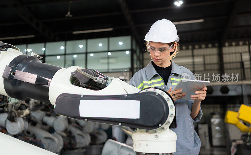 一名女工程师在机器人仓库的机器人手臂上安装程序。并在送机给客户前进行操作测试。