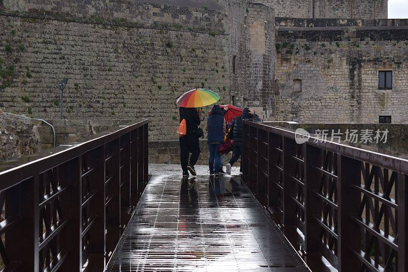 三个人在雨中撑着雨伞站在桥边