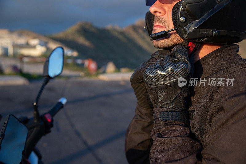 骑摩托车的人坐在摩托车上戴上头盔。