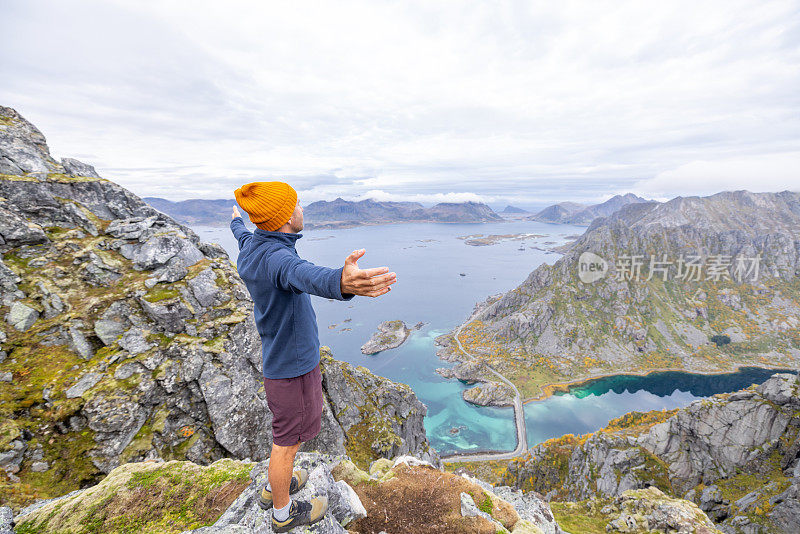 一名男子在挪威北部的山区徒步旅行，他伸开双臂拥抱大自然