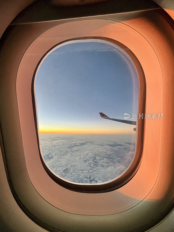 飞机经济舱从机场起飞后，从窗口鸟瞰日出天空。