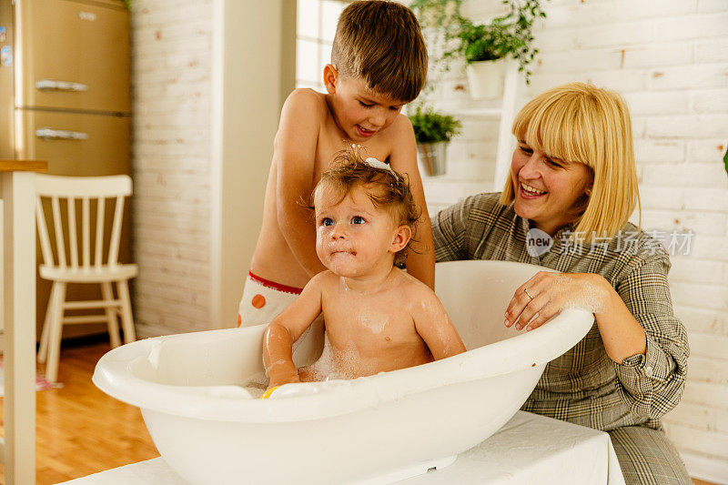 母亲在客厅的浴缸里给她的男婴洗澡