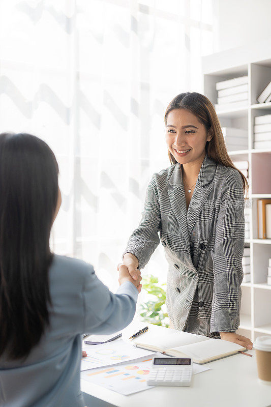 两位自信的女商人在成功会议、联系、问候和合作团队工作过程中握手。分析营销计划