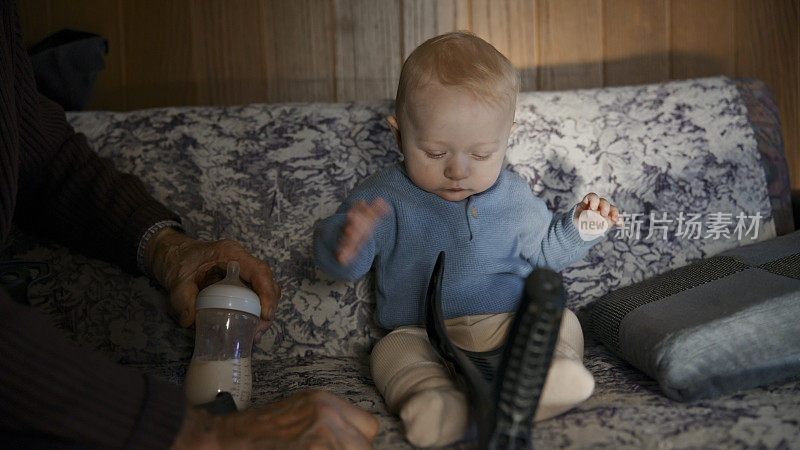 小男孩在沙发上玩爷爷的玩具。小男孩坐在客厅的沙发上玩爷爷的玩具