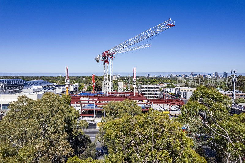 鸟瞰图零售购物中心建筑工地，两个塔式起重机和设备在阿德莱德东郊与城市CBD为背景。