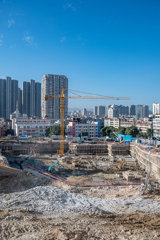 有垂直停车机器和远处城市建筑的建筑工地