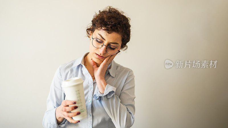 年轻女子牙痛，在白底前喝热咖啡。