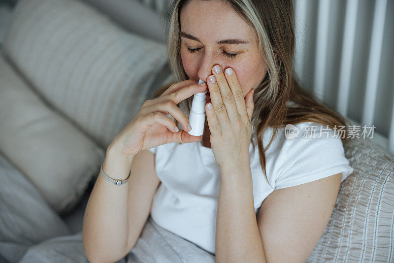 生病的年轻女子使用鼻腔喷雾剂