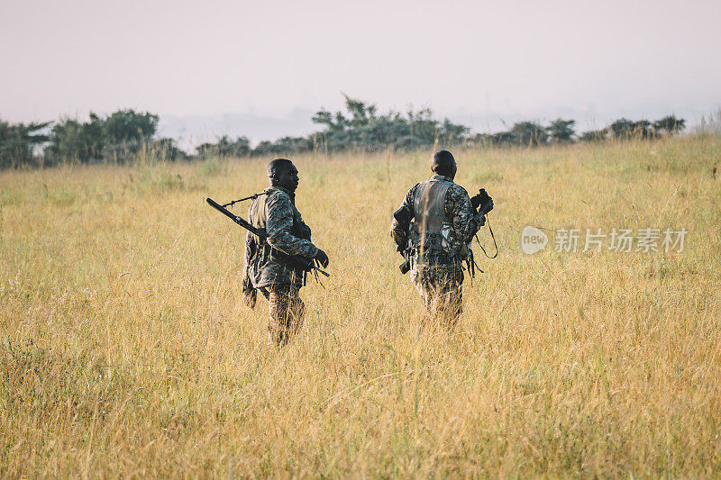 两个非洲士兵正穿行在高高的干草丛中，追踪野生动物。