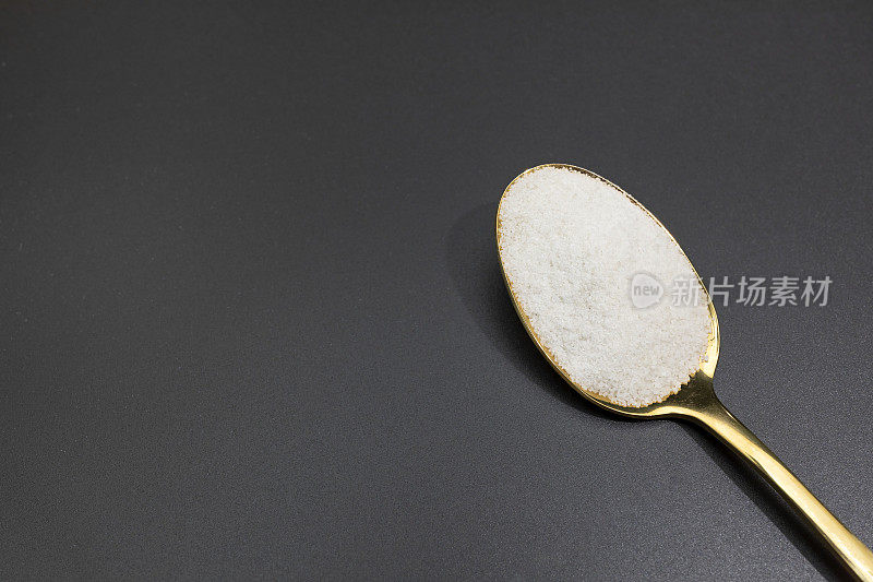 设计凯尔特灰色海盐在金色勺子在黑暗的桌子，复制空间。水平面。来自法国布列塔尼的天然和未精制盐。天然矿物质和微量元素，超级食物
