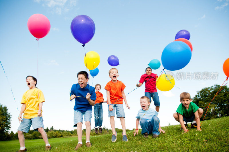 一群兴奋的男孩拿着气球在外面跳着、喊着
