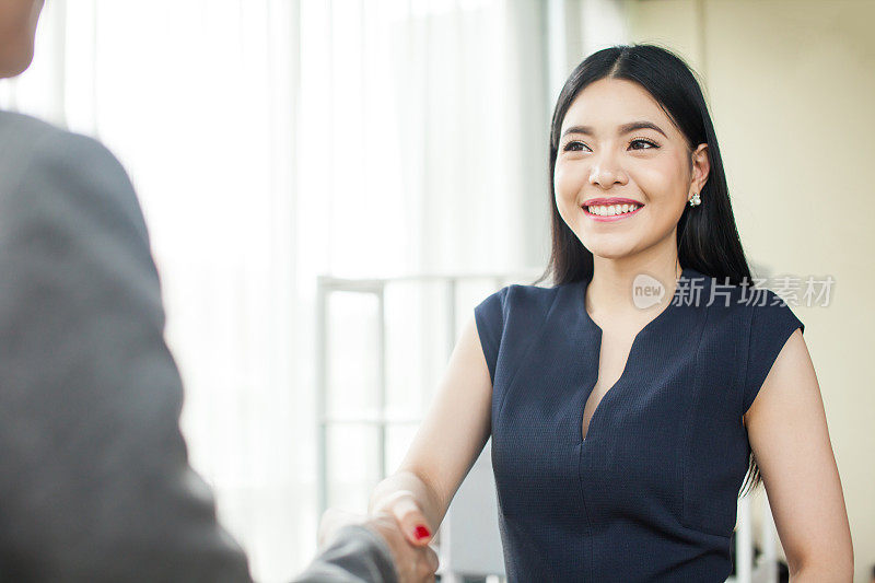 美丽的亚洲女商人微笑和握手