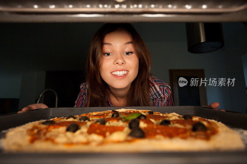 快乐女孩把披萨放进烤箱