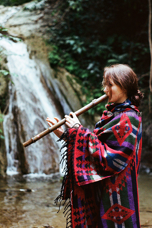 在瀑布附近拿着长笛的女人