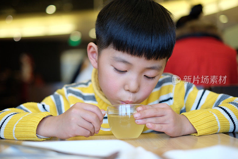 亚洲男孩在餐厅喝酒