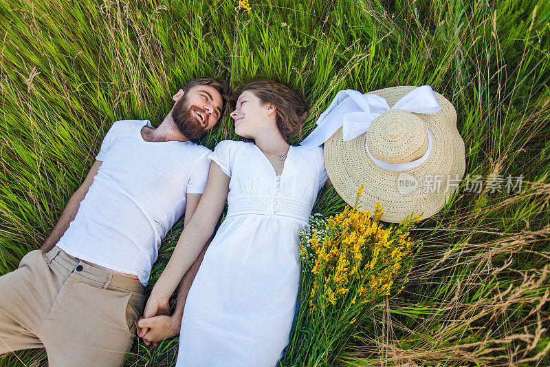 快乐的年轻夫妇在爱躺在草地上。