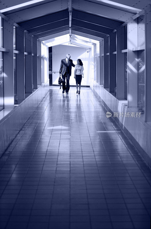 一男一女商人走在长廊上
