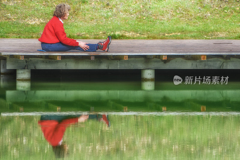 成熟的女人在湖边做瑜伽