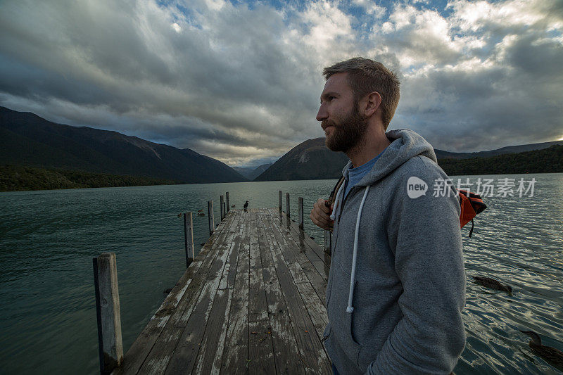 年轻人站在湖边的码头上看风景