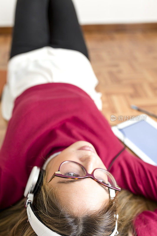 年轻的女学生用耳机听。