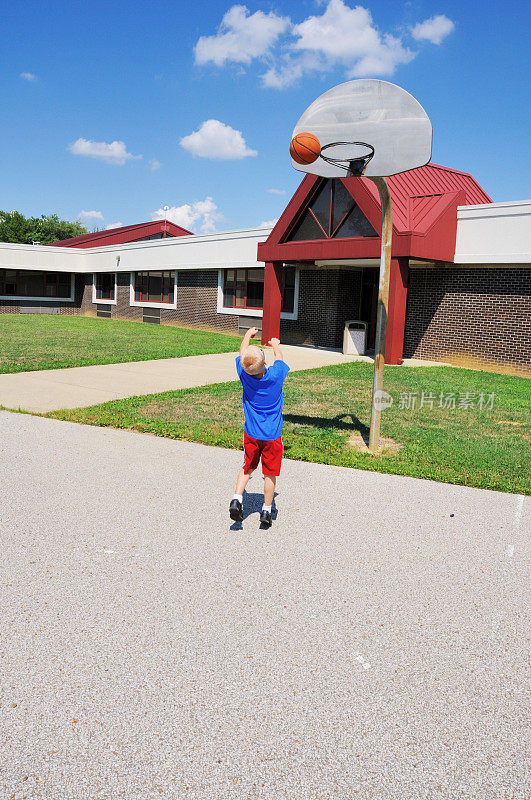 小男孩在学校操场上打篮球