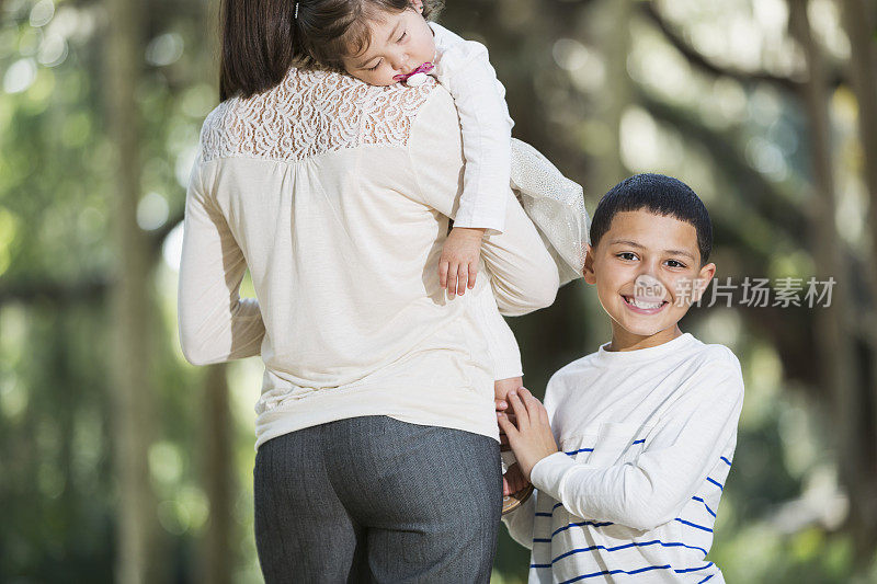 一个西班牙男孩和他的母亲和妹妹在公园里