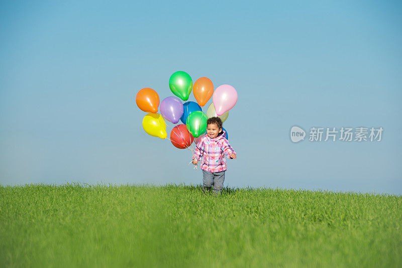 小女孩在野外拿着气球。