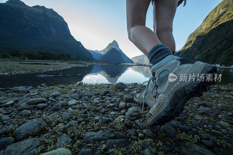 女士的腿和徒步靴站在米尔福德海湾，新西兰