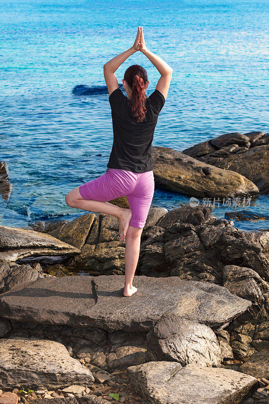 一个女人在海边的岩石上做瑜伽