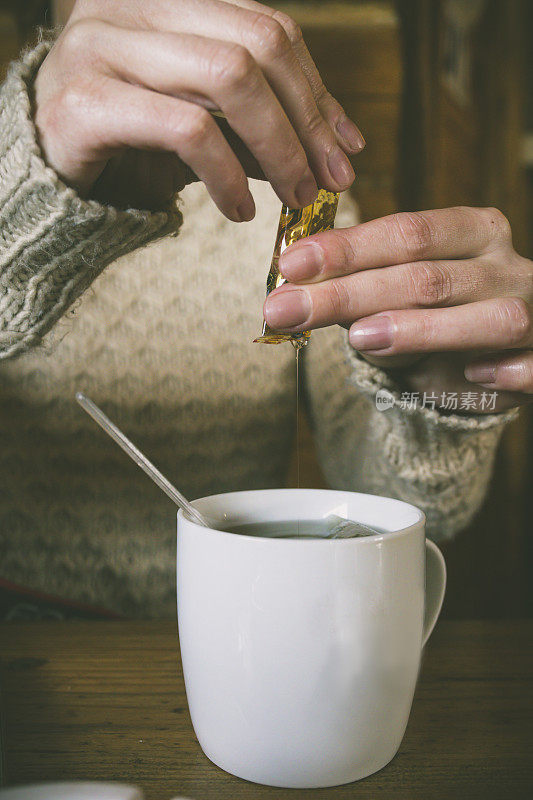 人的双手捧着一杯茶和蜂蜜。