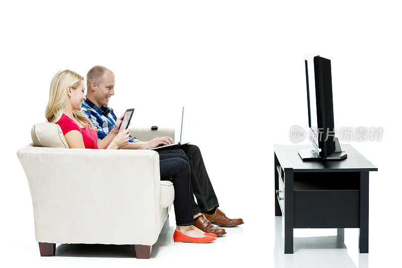 微笑的夫妇使用笔记本电脑和看电视